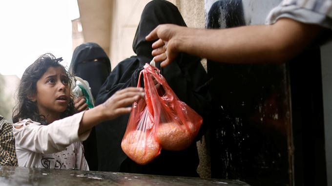A girl receives a rice ration at a food distribution center in Sanaa, Yemen